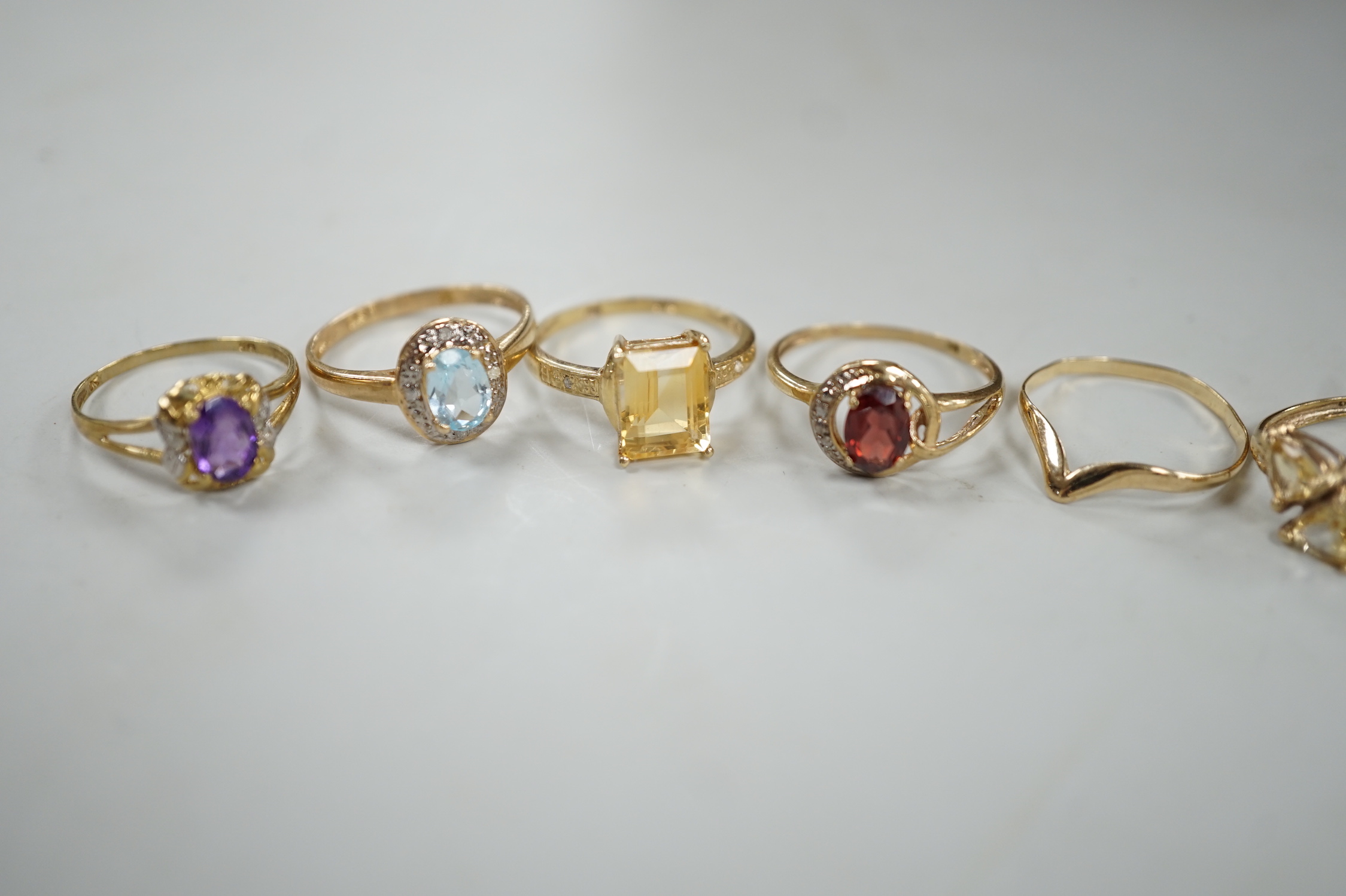 Five assorted modern 375 and gem set rings including amethyst and citrine, together with a 9ct wishbone shaped ring, gross weight 7.6 grams.